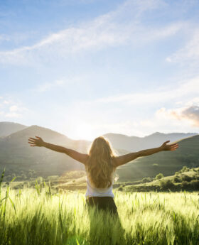 woman in nature with hands outstretched having a beautiful fresh morning
