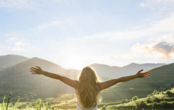 woman in nature with hands outstretched having a beautiful fresh morning