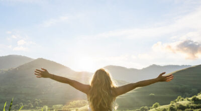 woman in nature with hands outstretched having a beautiful fresh morning
